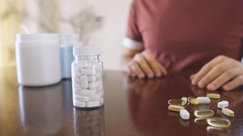 Closeup hand takes white tablets of vitamins and medicines sitting at the table Stock Footage 126271828