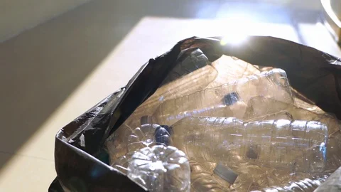 Closeup hand throwing plastic PET bottle into trash bag, slow motion Stock Footage 123959883