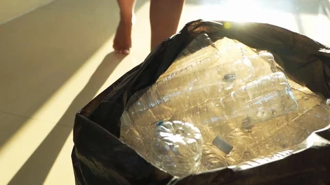 Closeup hand throwing plastic PET bottle into trash bag, slow motion Stock Footage 123960010