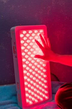 Closeup of hand touching Red Light Therapy Panel LEDs Stock Photos