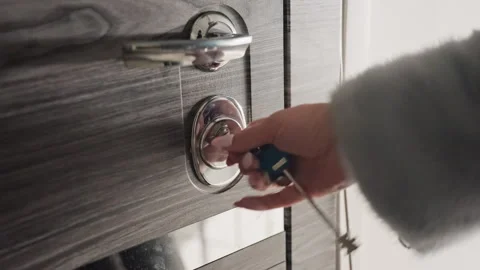 Closeup hand turning key in lock, gray coat sleeve visible, slow twist to unlock Stock-Footage 345139448
