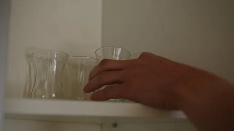 Closeup hand of unrecognizable housekeeper placing clean shot glasses on white Stock Footage 292561059
