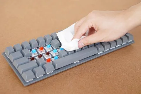 Closeup hand use tissue paper to clean wireless computer keyboard. Stock Photos