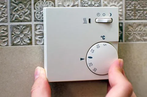 Closeup of hand using floor temperature controller at home Stock Photos