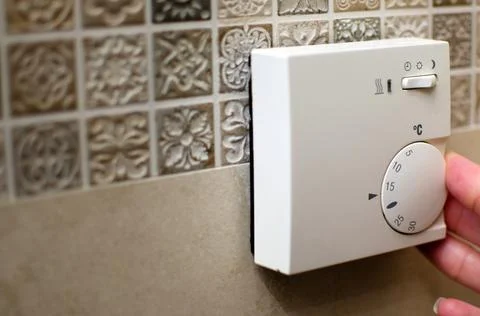 Closeup of hand using floor temperature controller at home Stock Photos