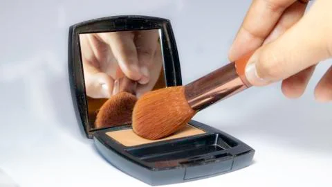 Closeup of hand using makeup brush and powder 스톡 사진