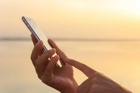 Closeup hand using phone during at sunset Stock Photos
