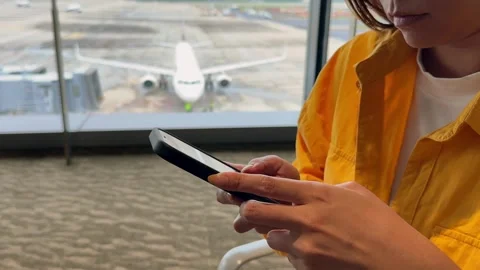Closeup of a hand using a smartphone in an airport terminal Stock Footage 307570887