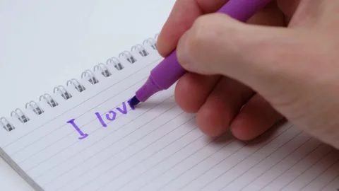 Closeup hand writes words I love you with marker and draws heart in notebook. Stock Footage 231454097