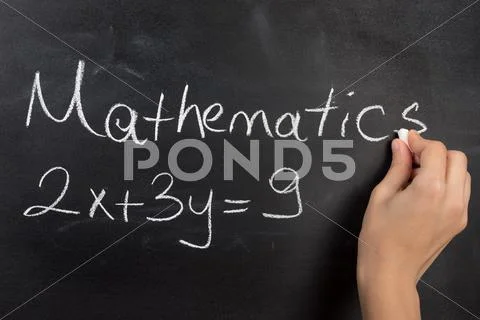 Closeup of hand writing complicated math equation on black board Stock Photos