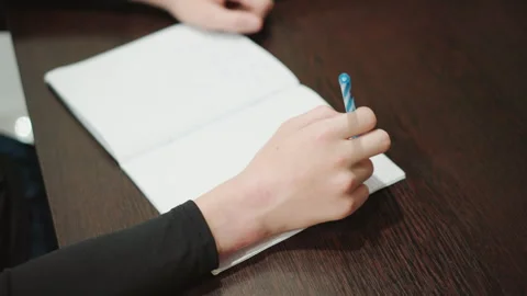 Closeup hand writing in notebook, young person studying at wooden desk, steady Video stock 332274236