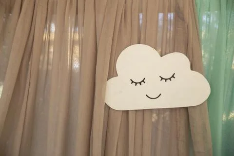 Closeup of a handmade paper cloud with a face on the curtains under the light 写真素材