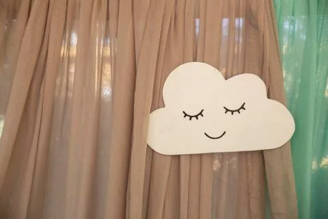 A closeup of a handmade paper cloud with a face on the curtains under the lights Stock Photos
