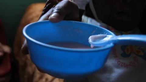 Closeup of hands and a plastic bowl with food being stirred by a spoon 動画素材 74792594