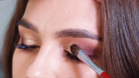 Closeup of hands applying shiny eyeshadows to young woman eyelids in slow motion Stock Footage 100981204