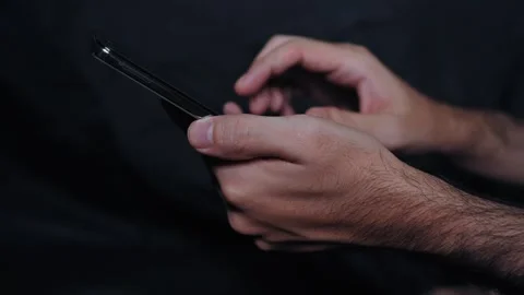 Closeup of Hands Browsing Mobile Phone on Dark Background 库存影片 337785142