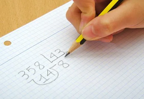 Closeup on the hands of a child doing maths. Division. School concept Stock Photos