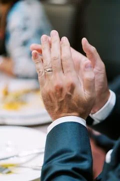 Closeup of hands clapping in celebration with elegant attire and ambient glow Stock Photos