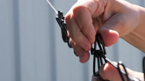 Closeup of hands clipping a laundry using clothespins to a clothesline rope Vidéo 292157082
