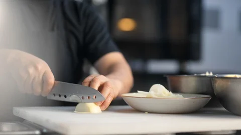 Closeup hands of cook staff cutting onion on table board using knife. 4k Dragon Video stock 124866448