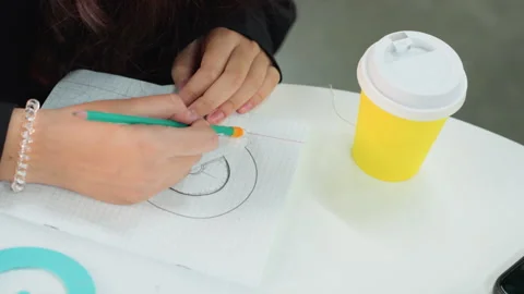 Closeup of hands creating art. Student working on creative spiral drawing at Stock Footage 331360977