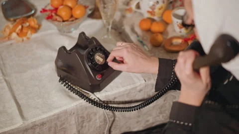 Closeup hands dialing vintage rotary phone on table with tea and tangerines Stock Footage 346563652