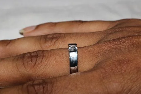 Closeup of hands with diamond ring on finger  wedding band on brown skin  e.. 写真素材