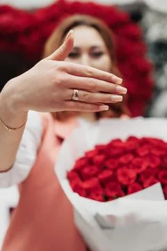 Closeup Hands Displaying Engagement Ring While Woman Holds Red Rose Bouquet In Foto stock