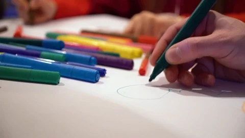 Closeup hands drawing on big paper sheet with focus on colored markers in Stock Footage 100908828