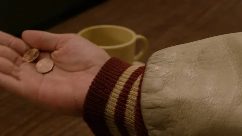 Closeup of hands dropping two pennies in jar Stock Footage 127962077