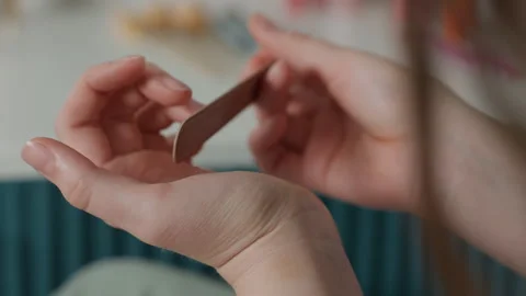 Closeup hands gently buffing nails, soft bedroom light, wooden buffer, relaxed Stock Footage 345170325