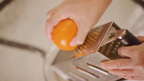 Closeup hands grating orange zest pumpkin pie filling, warm kitchen light Stock Footage 346394581