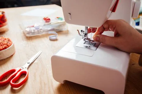 Closeup hands inserting thread into sewing machine needle Stock Photos
