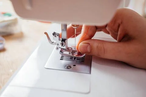 Closeup hands inserting thread into sewing machine needle Closeup woman s ... 写真素材