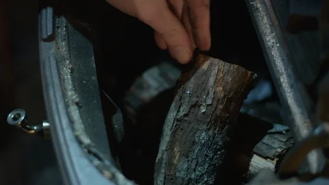 Closeup: Hands load firewood into the top of an old cast iron fireplace Stock Footage 101198978