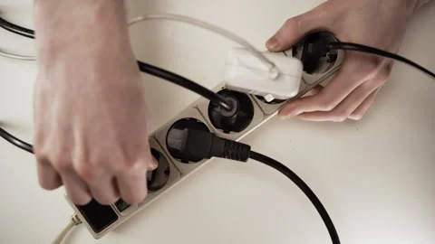 Closeup at the hands of men plugging plug into multiple socket switch. Stock Footage 309541647