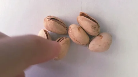 Closeup of hands opening a pistachio - background with many pistachios Stock-Footage 101275109