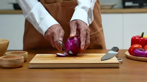 Closeup of hands peeling red onion in home kitchen with knife. Food prep, c.. Video stock 312978721