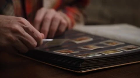 Closeup hands philatelist inserting stamps into collector's album with tweezers. Stock Footage 304646314