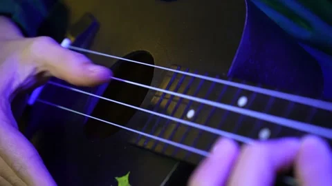 Closeup hands playing ukulele in evening. Purple illumination Stock Footage 237186079