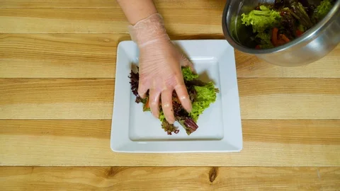 Closeup of hands putting salad, chopped tomatoes, onions, cheese, prosciutto Stock Footage 99793602