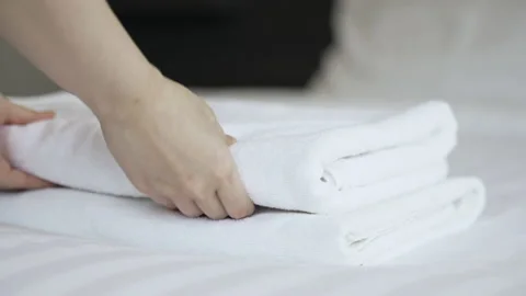 Closeup hands putting a stack of new clean bath towels on the bed Video stock 159861775