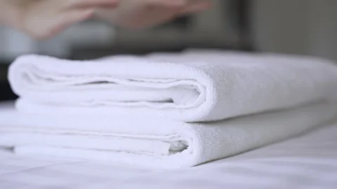 Closeup hands putting a stack of new clean bath towels on the bed Video stock 159862269