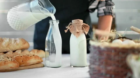 Closeup hands of rustic housewife pulling milk to glass bottles. Shot on RED Vídeos de archivo 136967062