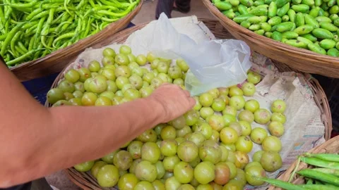 Closeup of hands selecting fresh Indian gooseberry at a market with a focus Stock-Footage 264939105