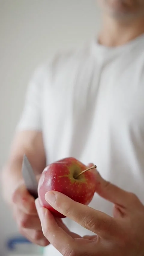 A closeup of hands skillfully slicing a fresh apple with a knife, showcasing Video stock 310726671