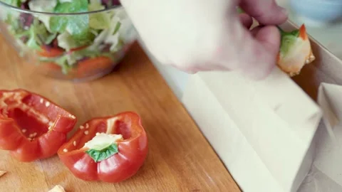 Closeup of hands slicing bell pepper and putting a waste into a paper trash bag. Video stock 305848910