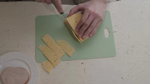 Closeup hands slicing cheddar Stockbeeldmateriaal 336611713