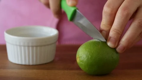 Closeup of Hands Slicing a Lime with a Knife and Squeezing out the Juice Stock Footage 91799789
