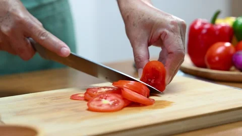 Closeup of hands slicing tomato with a sharp knife on wooden board in kitch.. Stock Footage 312978931
